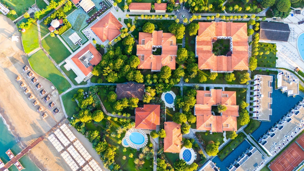 Aerial view of a luxury beachfront resort with private villas, pools, and lush gardens